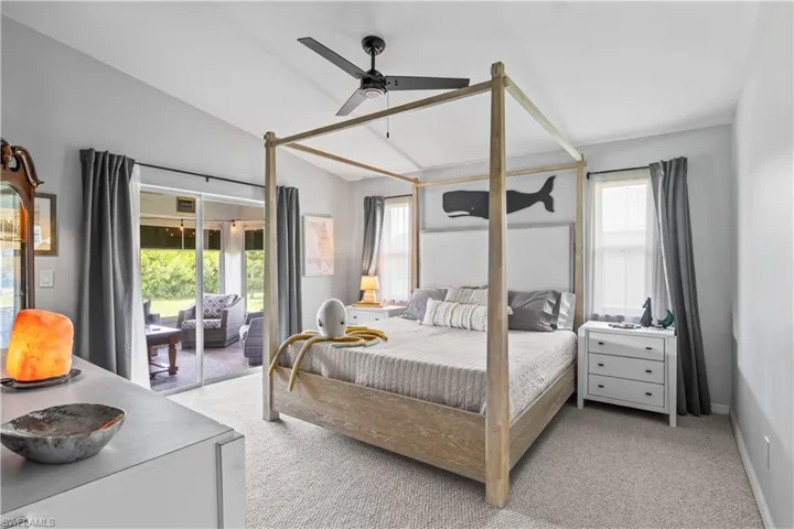 Bedroom with light colored carpet, access to exterior, lofted ceiling, and ceiling fan