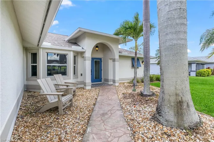 Entrance to property with a shingled roof and stucco siding