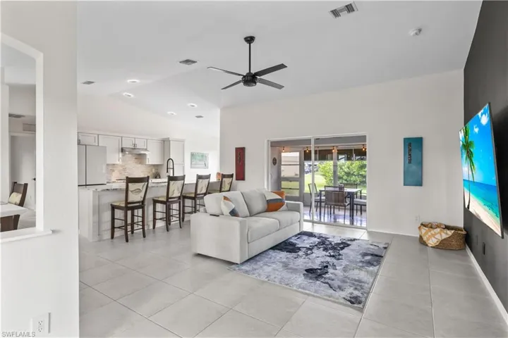 Living area featuring light tile patterned flooring, a ceiling fan, and lofted ceiling