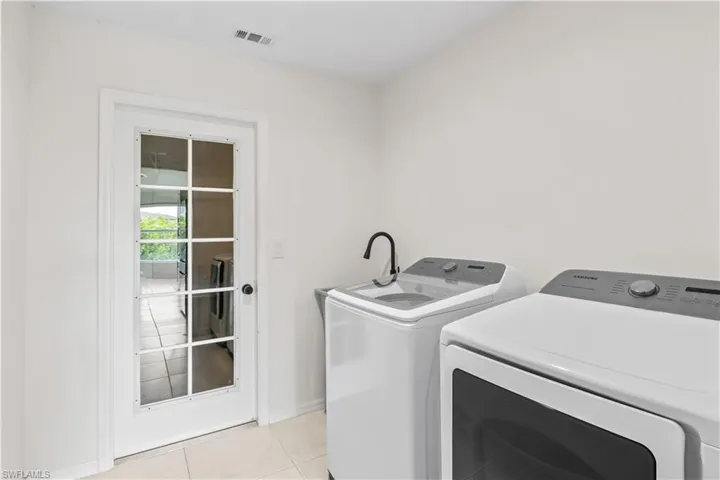 Laundry area with washing machine and clothes dryer and light tile patterned floors
