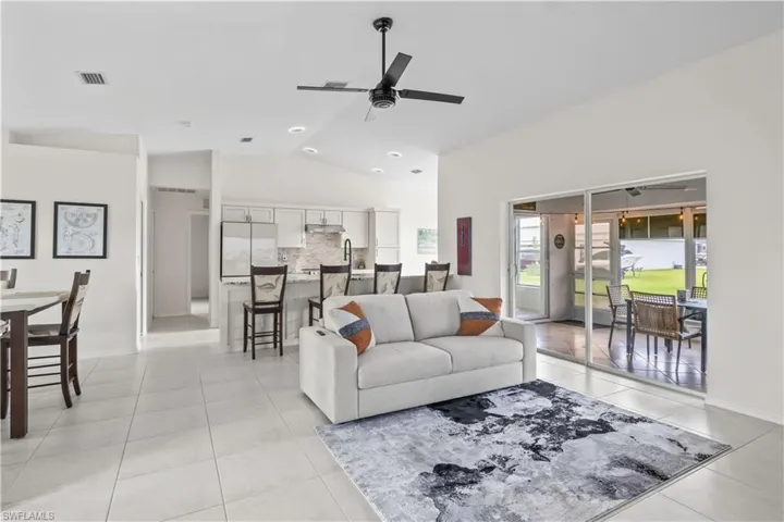 Living room featuring lofted ceiling, a ceiling fan, and light tile patterned floors