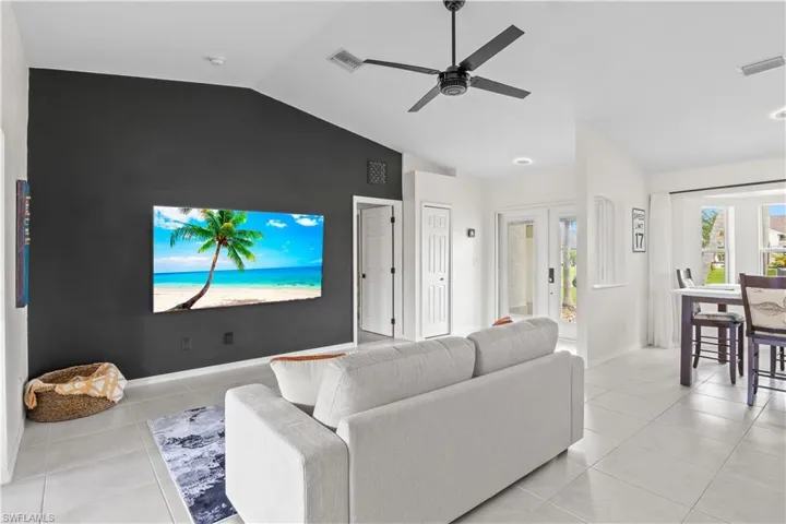 Living room featuring lofted ceiling, light tile patterned flooring, and ceiling fan