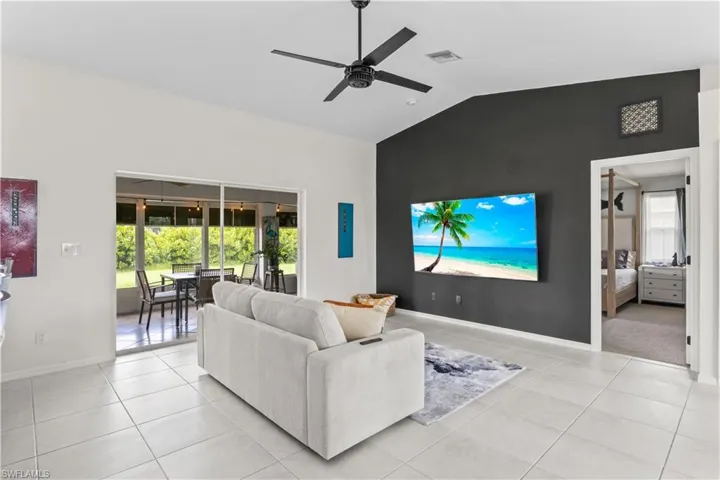 Living room with lofted ceiling, a ceiling fan, and light tile patterned flooring