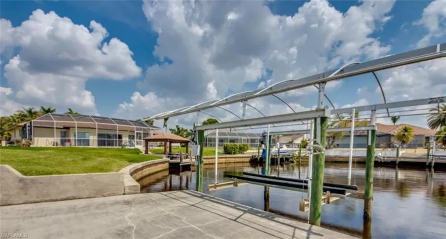 View of dock with a yard, a lanai, and a water view