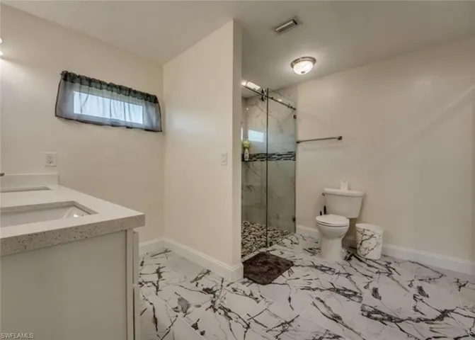 Bathroom with tile patterned flooring, toilet, dual bowl vanity, and walk in shower