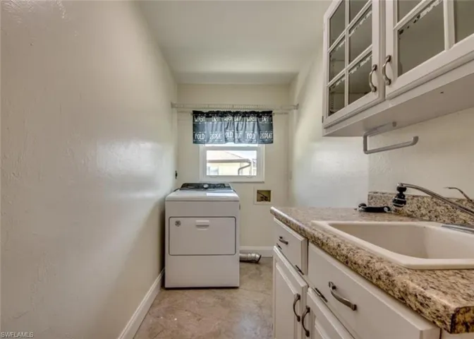 Laundry area featuring washer / clothes dryer, sink, light tile patterned floors, and cabinets