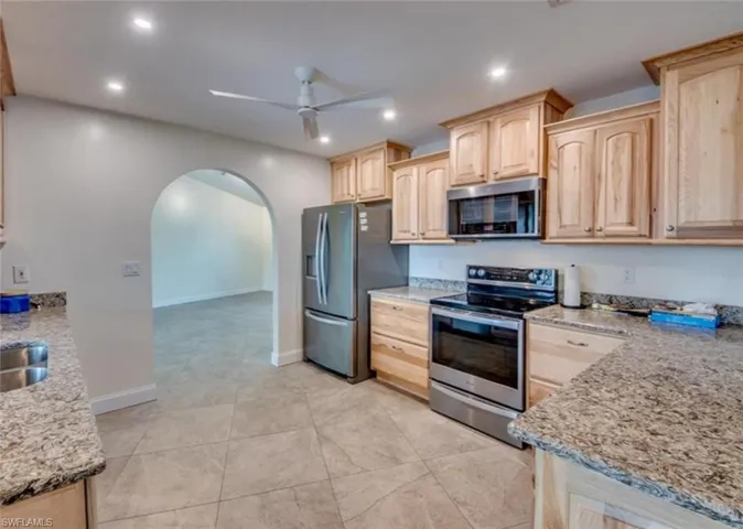 Kitchen with ceiling fan, light brown cabinets, appliances with stainless steel finishes, light stone countertops, and light tile patterned floors