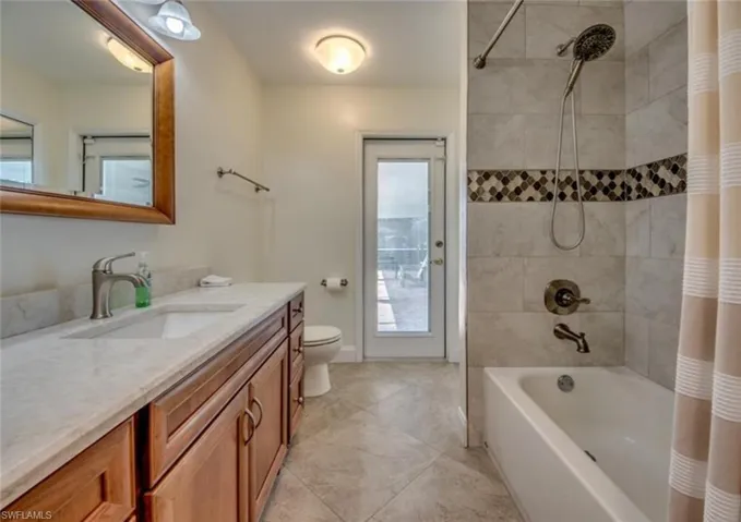 Full bathroom featuring tile patterned flooring, shower / bath combination with curtain, vanity, and toilet