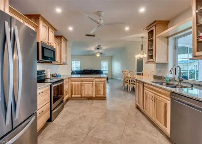 Kitchen with light tile patterned floors, sink, stainless steel appliances, and light brown cabinets