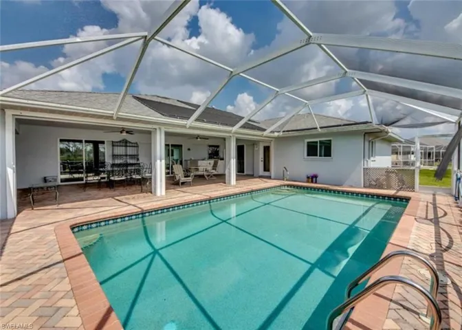 View of swimming pool featuring ceiling fan, a patio, and a lanai