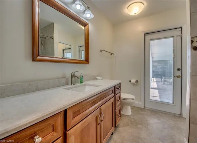 Bathroom with toilet, tile patterned floors, and vanity