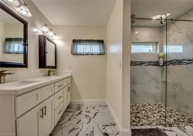 Bathroom featuring tile patterned flooring, double vanity, and a shower with shower door
