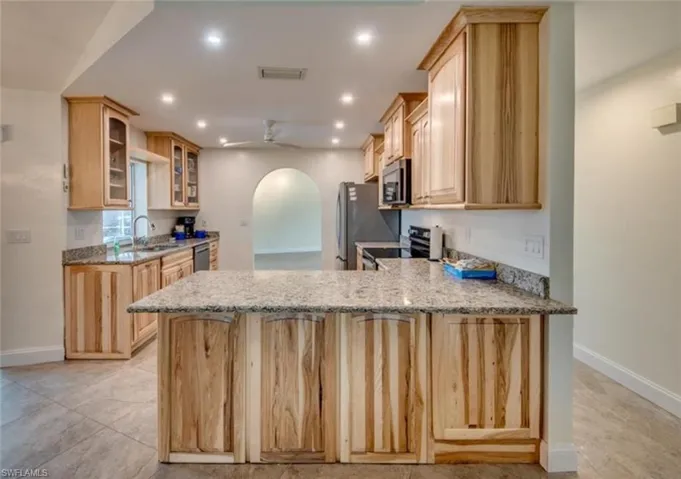 Kitchen featuring ceiling fan, kitchen peninsula, appliances with stainless steel finishes, and light stone countertops