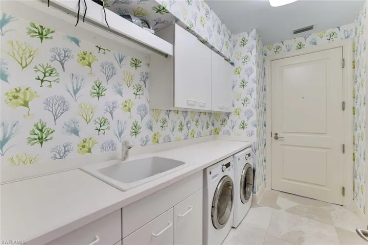 Laundry room with wallpapered walls, cabinet space, and independent washer and dryer