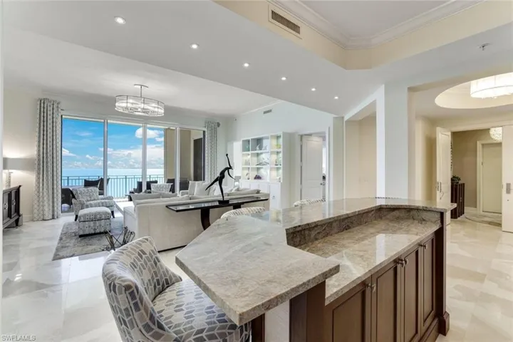 Kitchen with a chandelier, recessed lighting, light stone counters, crown molding, and open floor plan