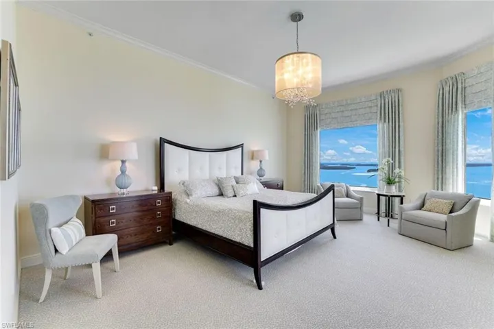 Bedroom with light colored carpet, a chandelier, crown molding, and baseboards
