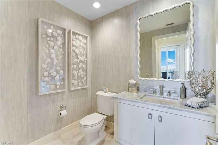 Half bath with toilet, baseboards, vanity, and tile patterned floors