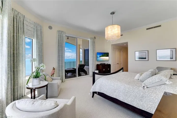 Carpeted bedroom featuring crown molding, access to exterior, and a chandelier