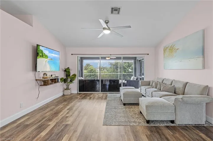 Living room with wood-type flooring, vaulted ceiling, and ceiling fan