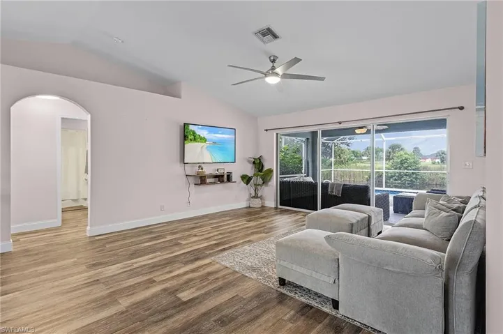 Living room with lofted ceiling, ceiling fan, and hardwood / wood-style flooring