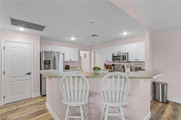 Kitchen with appliances with stainless steel finishes, a kitchen breakfast bar, and white cabinetry