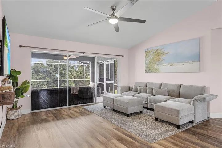 Living room featuring ceiling fan, vaulted ceiling, and wood-type flooring