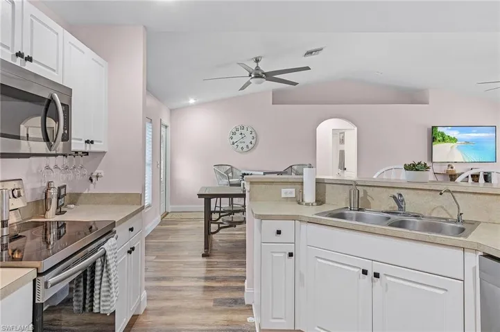 Kitchen featuring lofted ceiling, white cabinetry, light hardwood / wood-style flooring, stainless steel appliances, and ceiling fan