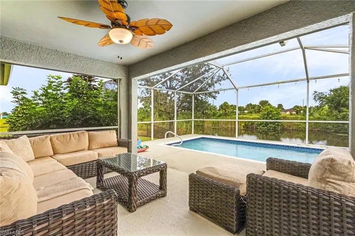 View of pool featuring an outdoor hangout area, a patio, a water view, glass enclosure, and ceiling fan