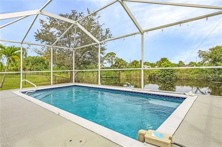 View of swimming pool with glass enclosure, a water view, and a patio