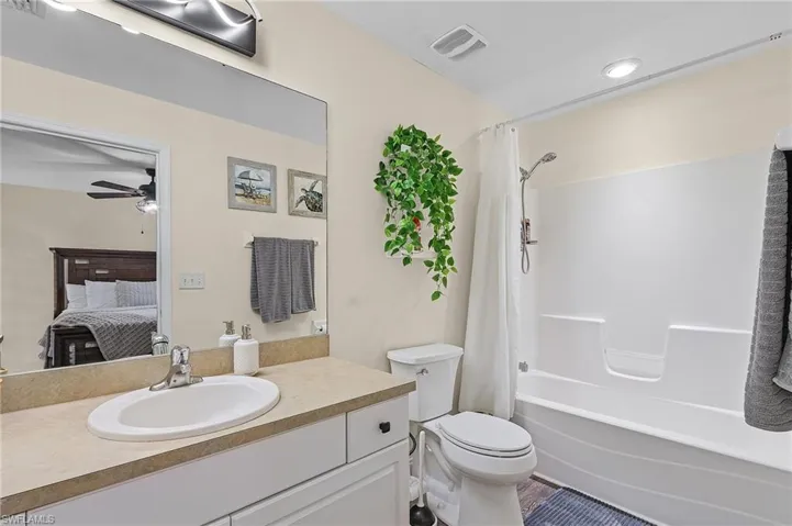 Full bathroom featuring shower / bath combination with curtain, ceiling fan, vanity, and toilet