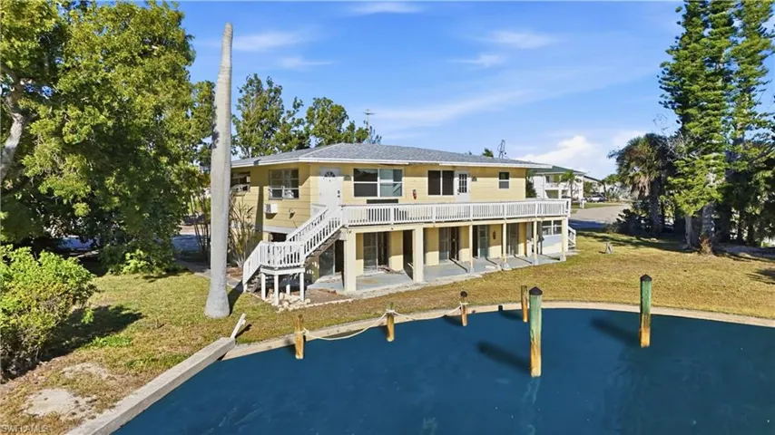 Back of property with a patio area, a yard, stairs, and a deck with water view - Virtually Edited Image