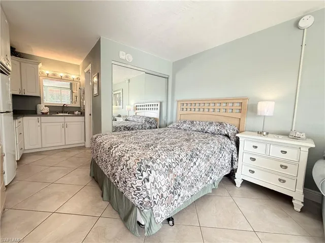 Bedroom featuring a closet, freestanding refrigerator, and light tile patterned floors
