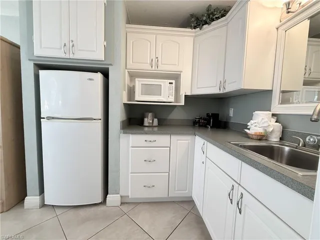 Kitchenette with white cabinetry, white appliances