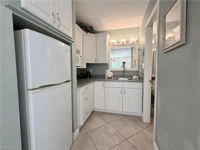 Kitchenette with white appliances, white cabinets