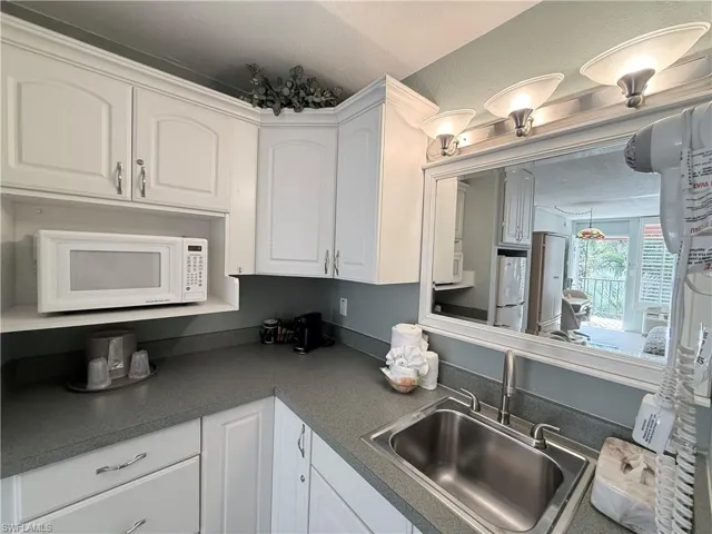 Kitchenette with white cabinetry, white appliances,