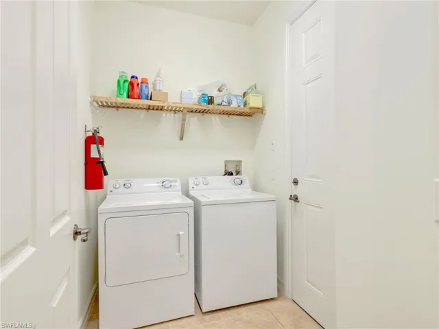 Washroom featuring light tile patterned flooring and washer and dryer