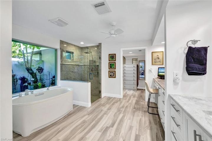 Primary bathroom has a separate soaking tub and a walk in shower w/ frameless door