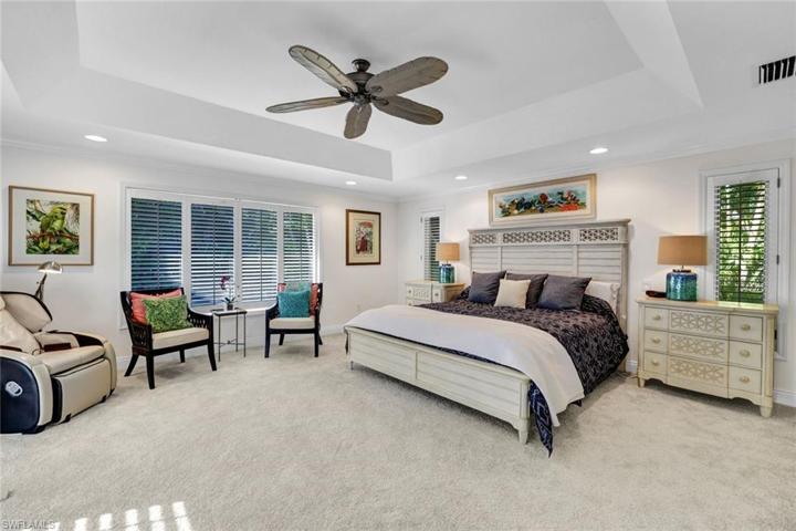 Oversized primary bedroom with tray ceiling and tons of windows