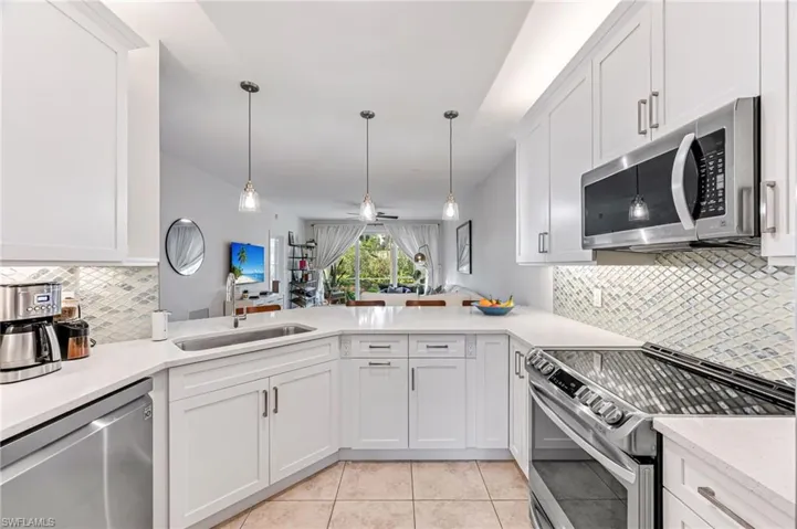 Kitchen featuring sink, decorative light fixtures, stainless steel appliances, and white cabinets