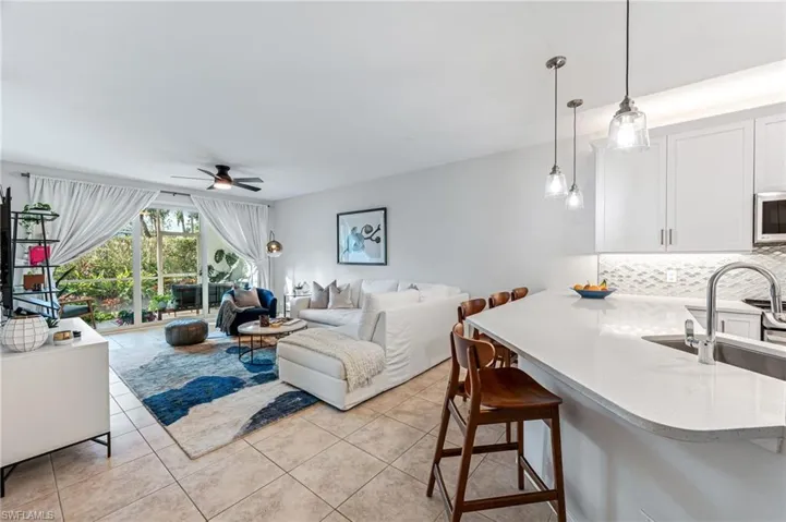 Living room featuring light tile patterned flooring, ceiling fan, and sink