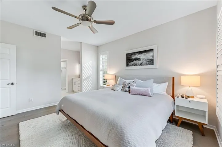 Bedroom with dark hardwood / wood-style flooring, connected bathroom, and ceiling fan