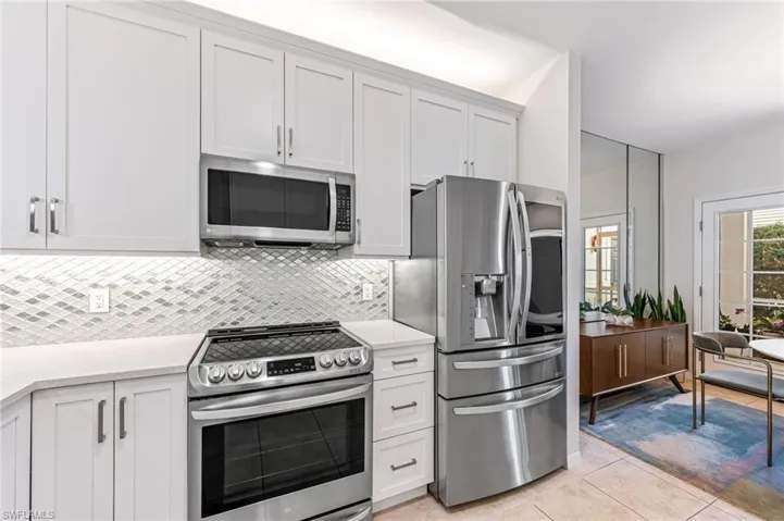 Kitchen with stainless steel appliances, light tile patterned floors, and white cabinets