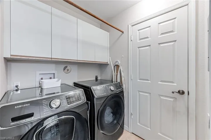 Clothes washing area featuring separate washer and dryer and cabinets