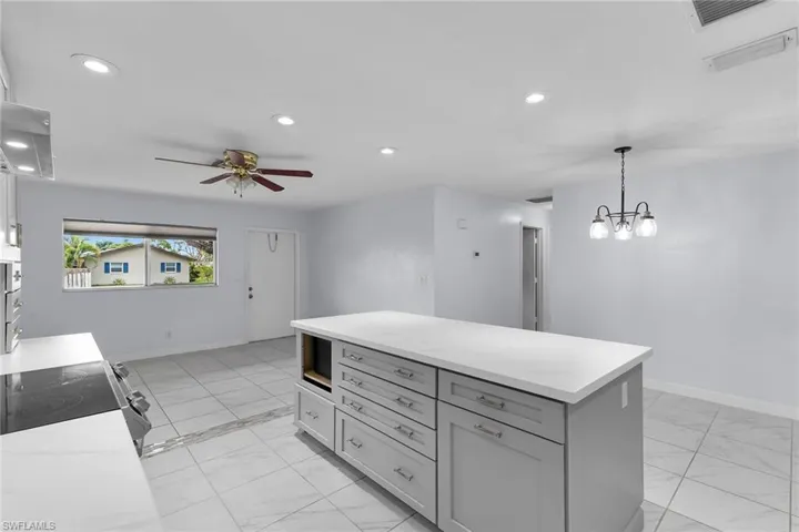 Kitchen featuring recessed lighting, a center island, hanging light fixtures, gray cabinets, and range with electric cooktop