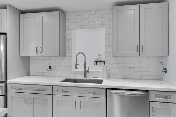 Kitchen featuring appliances with stainless steel finishes, light stone counters, and decorative backsplash