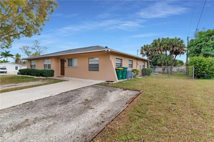 View of property exterior with stucco siding, a gate, and driveway