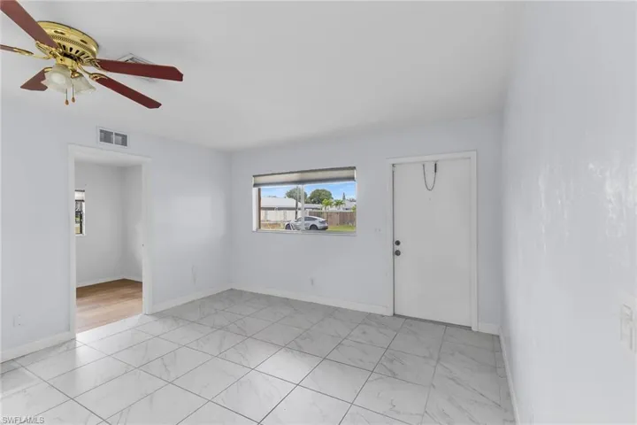 Empty room featuring light marble finish floors and ceiling fan