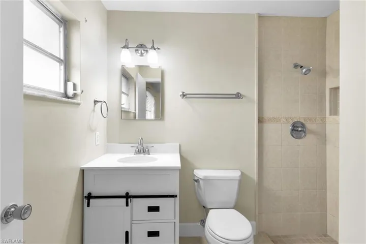 Full bath featuring a tile shower and vanity