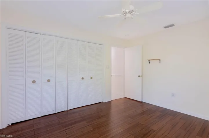Unfurnished bedroom featuring dark wood-type flooring, ceiling fan, and a closet