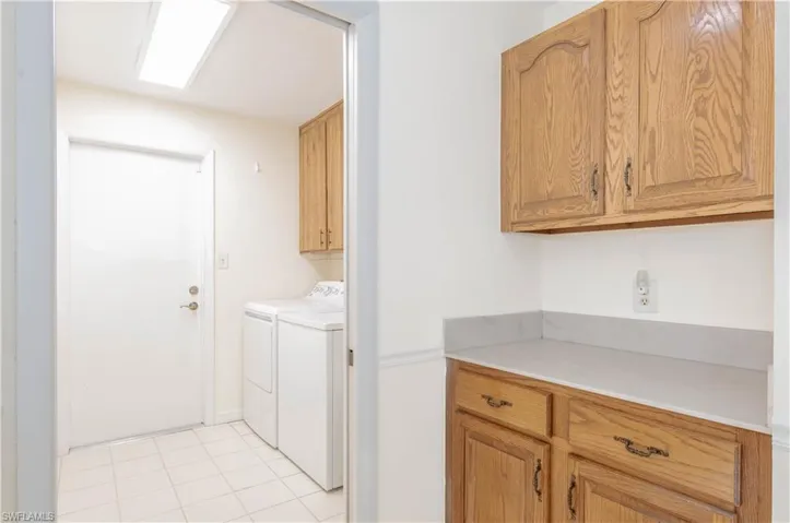 Laundry room with cabinets, washer and clothes dryer, and light tile patterned floors
